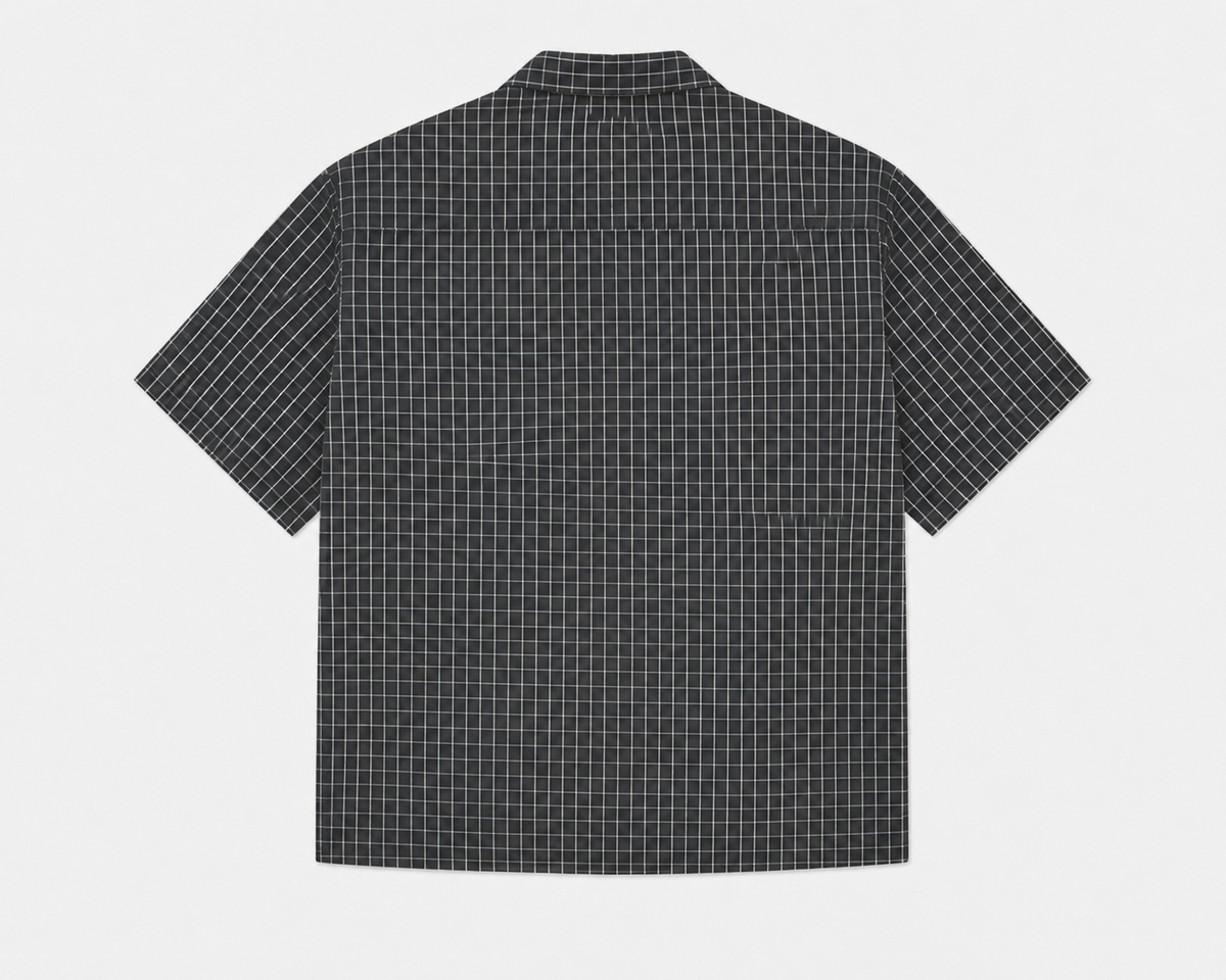 A short-sleeve button-up shirt with a black and white grid pattern, shown from the back against a light gray background.
