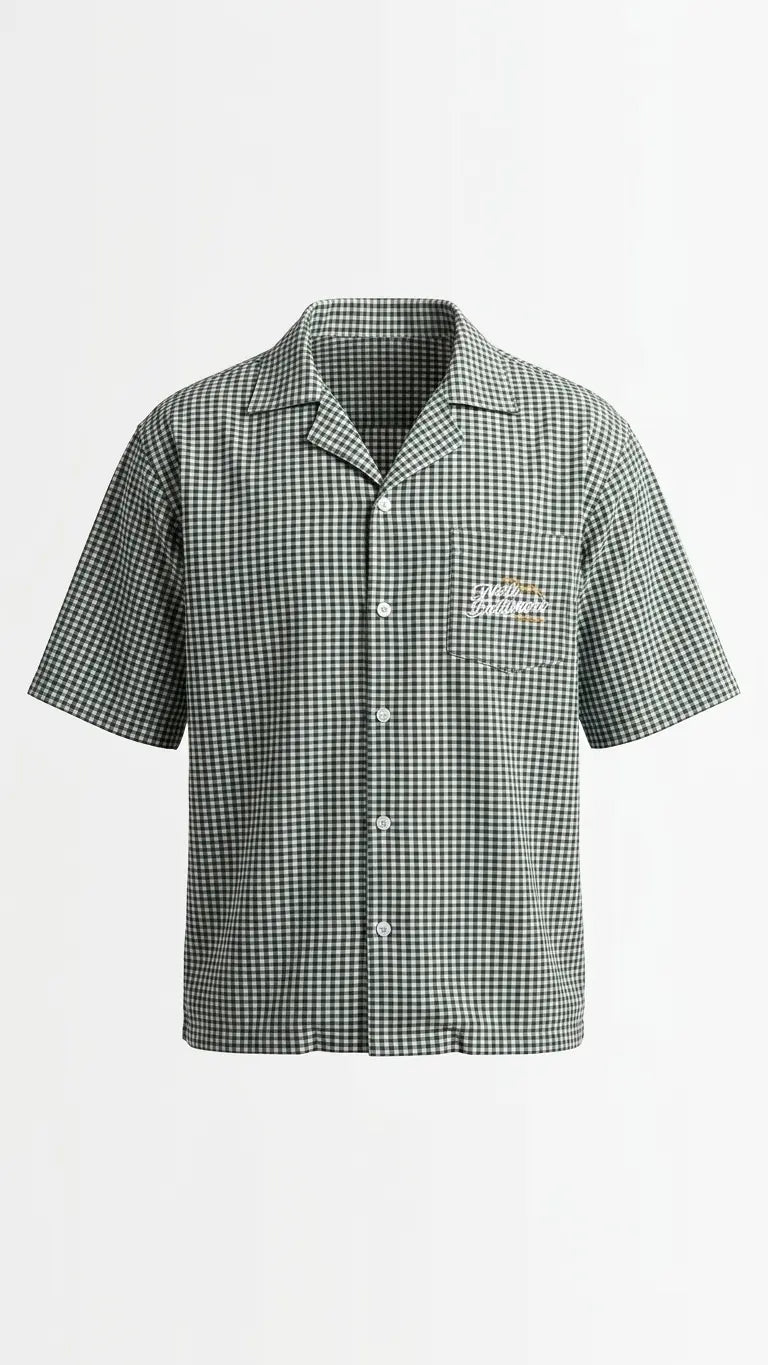 A short-sleeve button-up camp shirt with a green and white gingham check pattern, featuring a chest pocket with a small embroidered logo on the left chest, displayed on a clean white background.